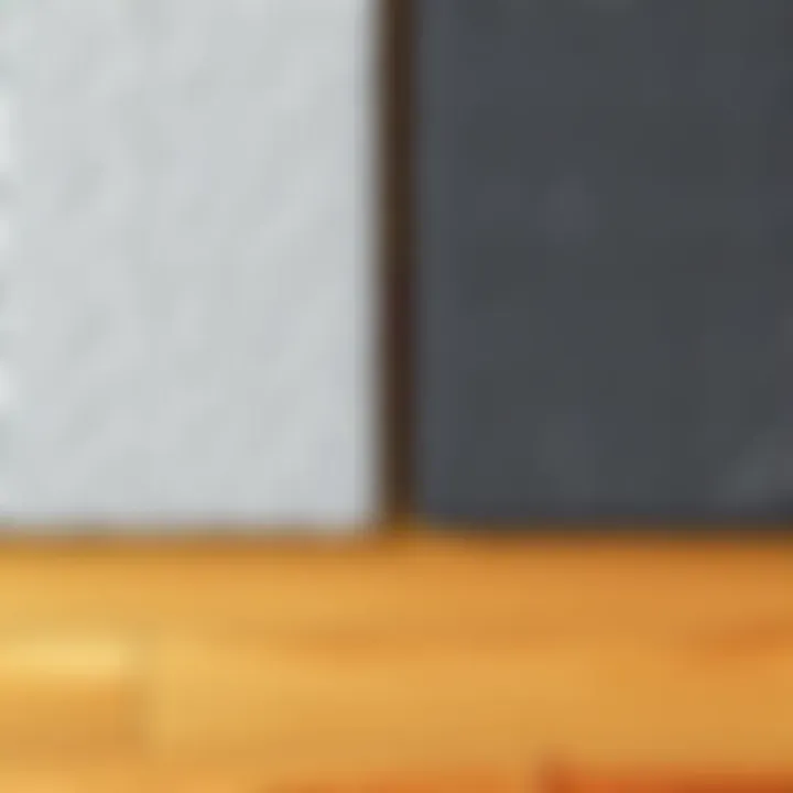 Two carpet samples, one light gray and one dark gray, placed side by side on a wooden floor. Each sample shows texture and color variation.
